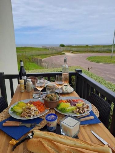 une table avec deux assiettes de nourriture et des verres de vin dans l'établissement Joli studio près du front de mer, à Cabourg