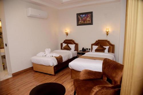a hotel room with two beds and a chair at The Rich Hotel & Apartments in Lahore