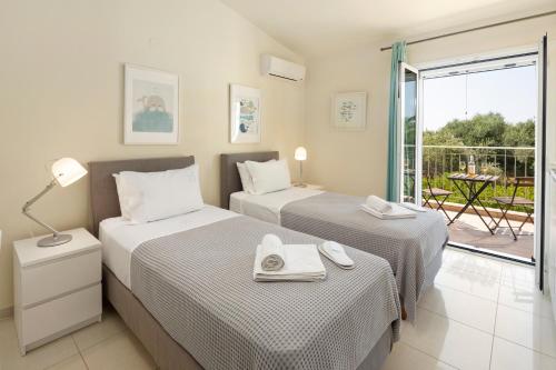 two beds in a room with a balcony at Skales Villas in Almiros Beach