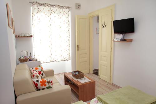 - un salon avec un canapé, une chaise et une télévision dans l'établissement Room Mira, à Trogir
