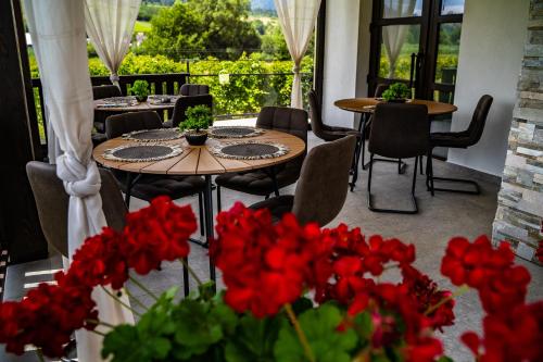 un patio con mesas, sillas y flores rojas en Casa Românească, en Putna