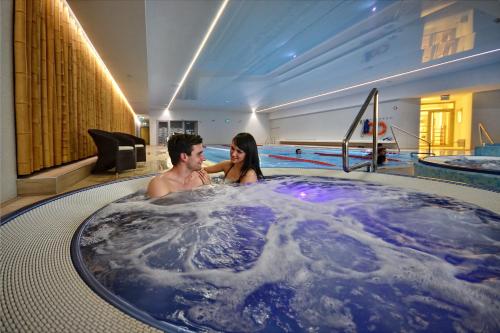 a man and woman in a hot tub in a swimming pool at Hotel Bażantowo Sport in Katowice