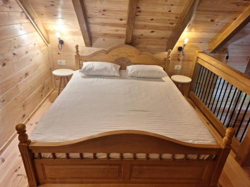 a large bed in a wooden room with two tables at Riverland Cottage 1 in Kolašin
