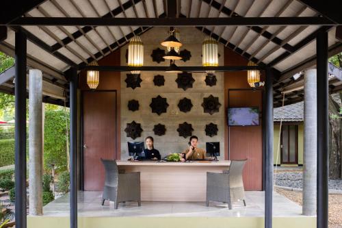 zwei Personen sitzen an einer Bar auf einer Terrasse in der Unterkunft U Inchantree Kanchanaburi in Kanchanaburi