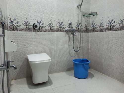 a bathroom with a shower with a toilet and a blue trash can at Atithya Resort in Khānāpāra