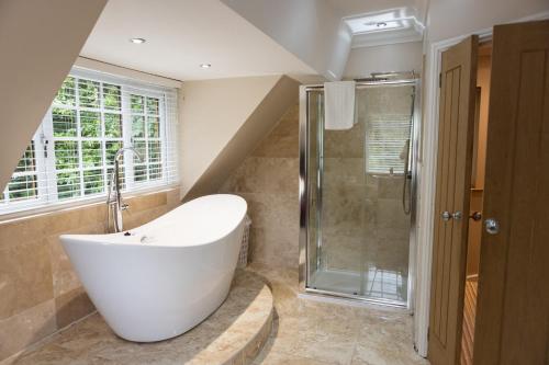 een badkamer met een wit bad en een douche bij Romantic Cottage in Plymouth