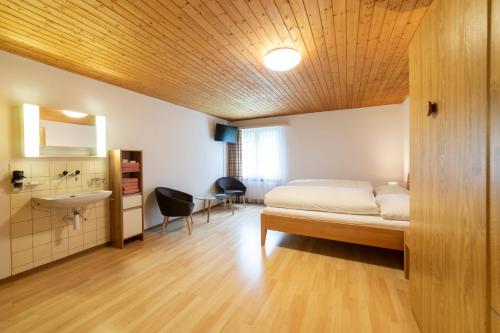 a bedroom with a bed and a bathroom with a sink at Hotel Sonne in Wildhaus