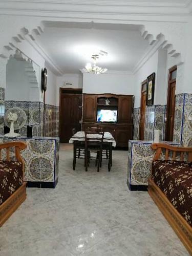 ein Wohnzimmer mit einem Tisch und einem TV in der Unterkunft المضيق الرينكون in Mʼdik