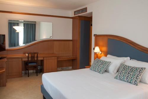 a bedroom with a white bed with a desk and a computer at Hotel Centrale in Sabaudia