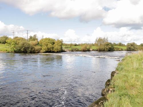 a river near a field with trees and clouds in the sky at 7 Aikenhead Terrace in Foxford