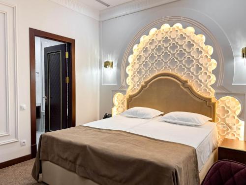 a bedroom with a large bed with a large headboard at Reikartz Sote Tashkent in Tashkent