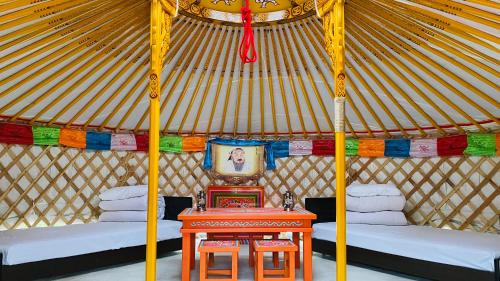 a room with two beds and a table in a yurt at miniモンゴルキャンプ場 in Gujo