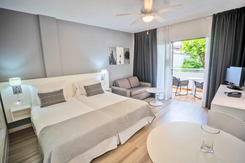 Habitación de hotel con cama grande y sala de estar. en Coral California - Adults Only, en Playa de las Américas