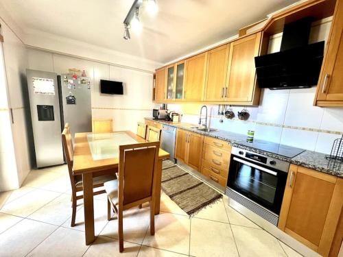 une cuisine avec des placards en bois et une table en bois avec des chaises dans l'établissement Appartement en duplex T3 - MER, à Peniche