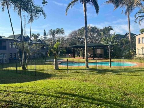 a fence around a swimming pool in a park with palm trees at The Bridge No 37 in St Lucia