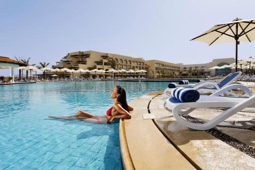 Eine Frau, die am Pool sitzt in der Unterkunft Movenpick Waterpark Resort & Spa Soma Bay in Hurghada