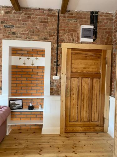 a room with a wooden door and a brick wall at Anny Łajming 2D in Słupsk