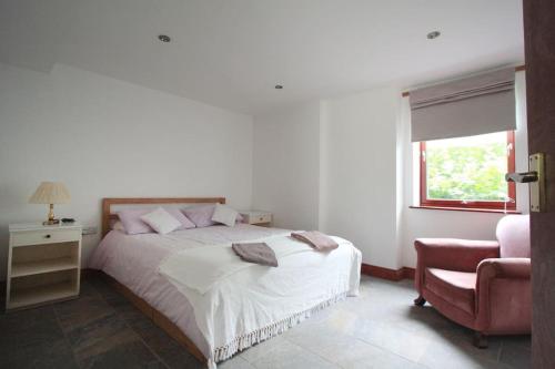 een slaapkamer met een bed, een stoel en een raam bij A nicely presented friendly comfortable cottage in Thornbury