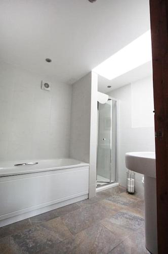 a white bathroom with a tub and a sink at A nicely presented friendly comfortable ECO cottage in Thornbury