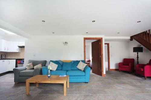 a living room with a blue couch and red chairs at A nicely presented friendly comfortable ECO cottage in Thornbury