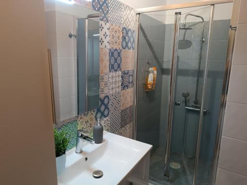 a bathroom with a sink and a glass shower at Airport Family House in Artemida