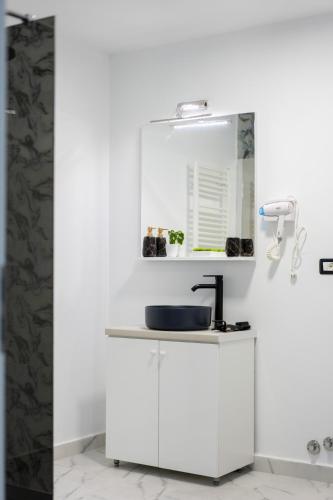 a white bathroom with a sink and a mirror at Casuta din drumul muntelui in Drăguş