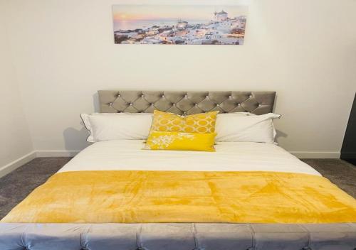 a bed with a yellow blanket on top of it at Luxury New Home in Kent