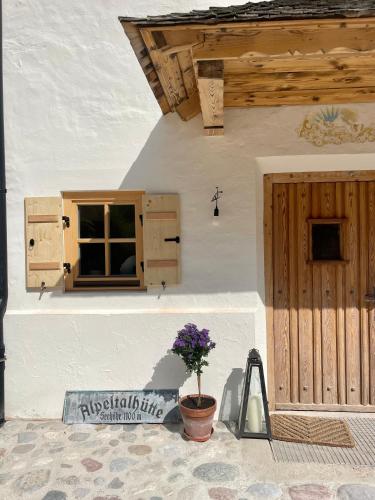 a white building with a window and a potted plant at Alpeltalhütte in Schönau am Königssee
