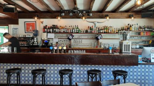 un bar avec un homme debout derrière un comptoir dans l'établissement Hotel Trinquet, à Saint-Pée-sur-Nivelle