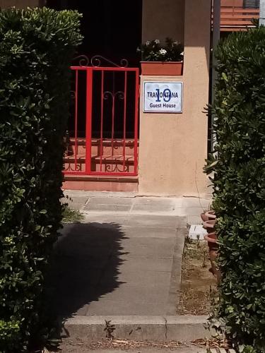 a red gate in front of a building with a sign on it at Guest House Tramontana 19 in Porto Ercole