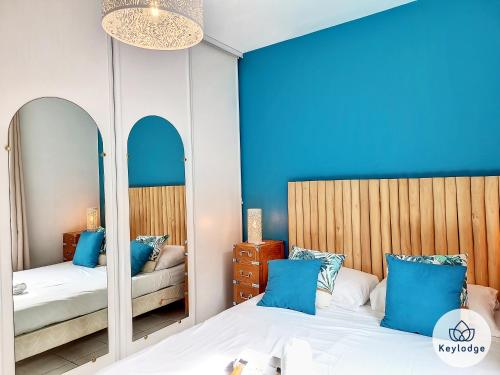 um quarto com 2 camas com paredes azuis e espelhos em Ti Paradis, 3 etoiles à deux pas du centre de Saint-Gilles em Saint-Gilles-les-Bains