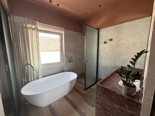 un bagno con una grande vasca bianca e una finestra di Igisó a Ermoupoli