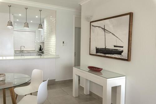 a kitchen with a table and a picture of a boat on the wall at 17 Bronze Beach Umhlanga Rocks in Durban