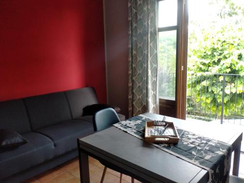 ein Wohnzimmer mit einem Sofa, einem Tisch und einem Fenster in der Unterkunft Da antonella in Cerretto Langhe