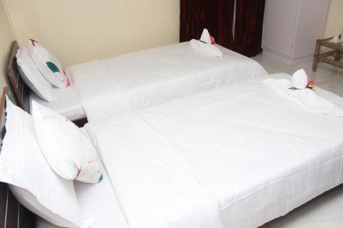 two beds in a room with white sheets and pillows at AESTHETICS - THE HOME STAY in Shillong