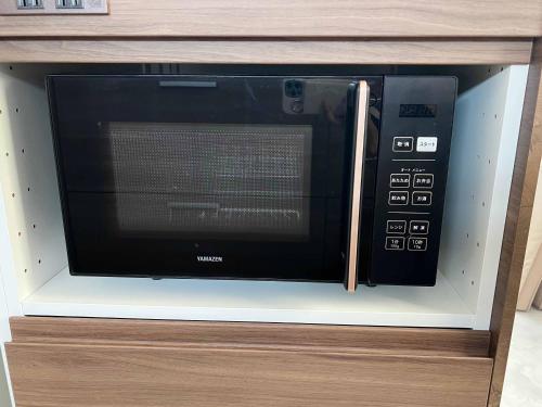 a microwave oven sitting inside of a wooden cabinet at Rainbow Village（レインボーヴィレッジ） in Mihama