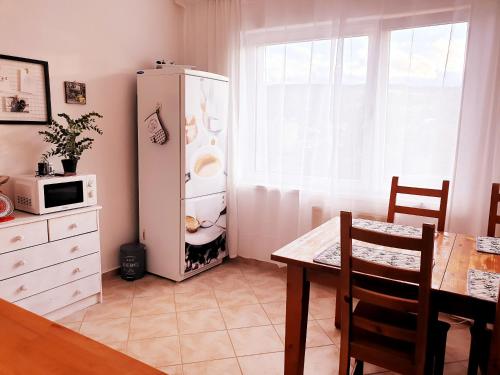 a kitchen with a table and a white refrigerator at Apartmán Terminál, self check-in 24 h in Banská Bystrica