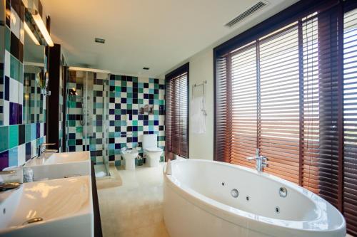 a bathroom with a tub and two sinks and a toilet at Axis Porto Business & Spa Hotel in Porto