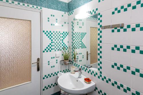 a bathroom with green and white tiled walls and a sink at My Grandparents' Home in Ropanianá