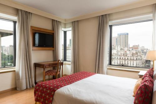 Habitación de hotel con cama, escritorio y ventanas en Imperial Park Hotel en Buenos Aires