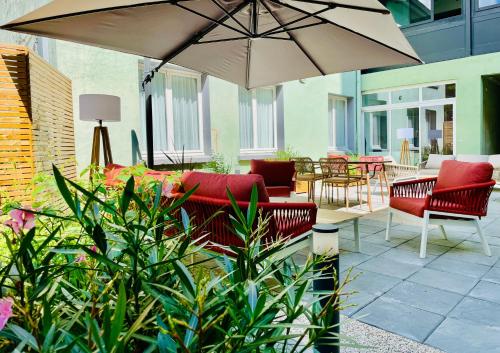 eine Terrasse mit Stühlen, einem Sonnenschirm und Tischen in der Unterkunft Hôtel Villa Berlioz in Lyon