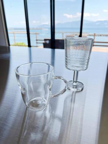 a glass coffee cup sitting on a table with a view at Rainbow Village（レインボーヴィレッジ） in Mihama