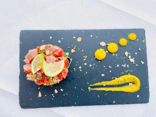 a black plate with food on it with a sandwich and a pickle at Hotel Mediterraneo in Lido di Latina 
