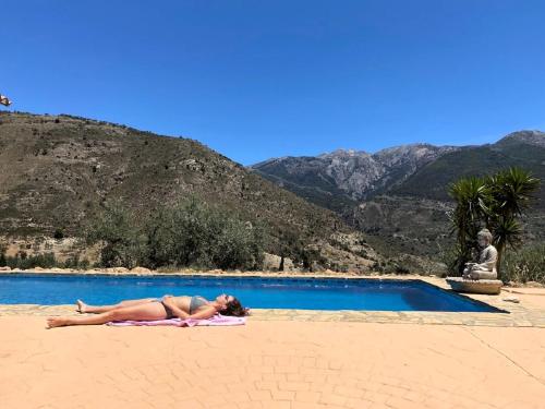 a woman laying on a towel next to a swimming pool at Harmony Home in Alcaucín
