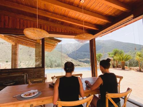 two women sitting at a table looking out at the mountains at Harmony Home in Alcaucín