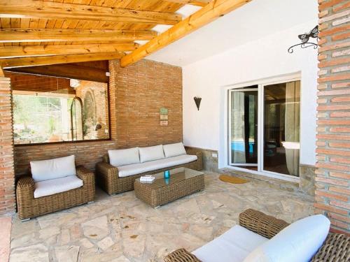 a patio with wicker furniture and a brick wall at Harmony Home in Alcaucín