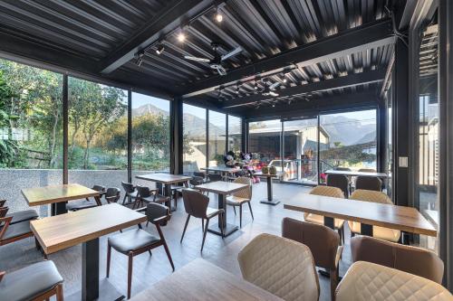 un restaurante con mesas, sillas y ventanas grandes en Caolingdai BnB, en Gukeng