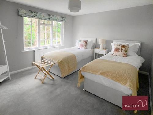 a bedroom with two beds and a window at Weybridge - 4 Bedroom Home - Driveway & Garden in Walton-on-Thames