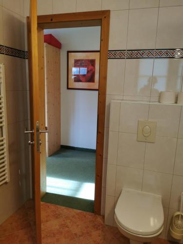 ein Bad mit WC und eine Tür zu einem Zimmer in der Unterkunft Ferienhof Jugendherberge Wurm in Stummerberg