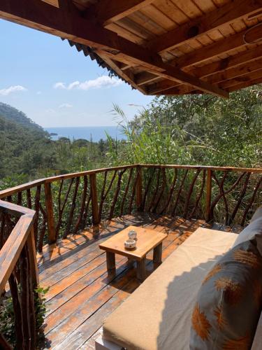 a wooden deck with a table on top of it at Bamboo Bungalow with Sea View in Kabak Bay, Ölüdeniz in Fethiye